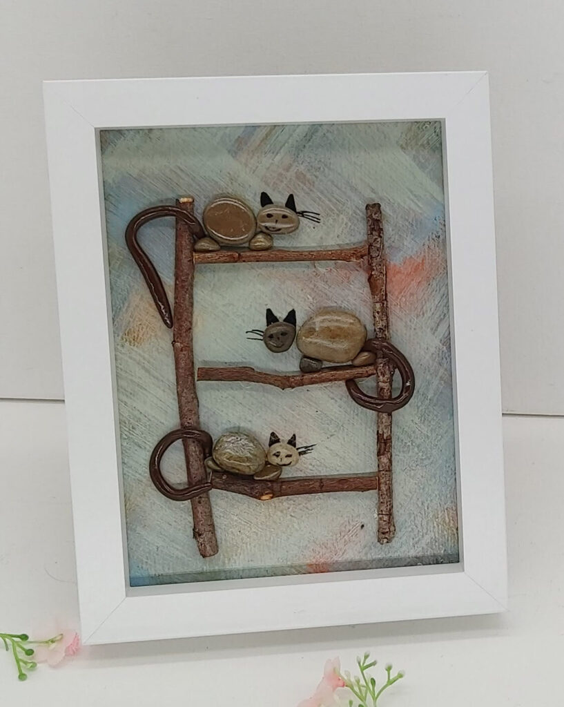 3 chats en galets sur une échelle