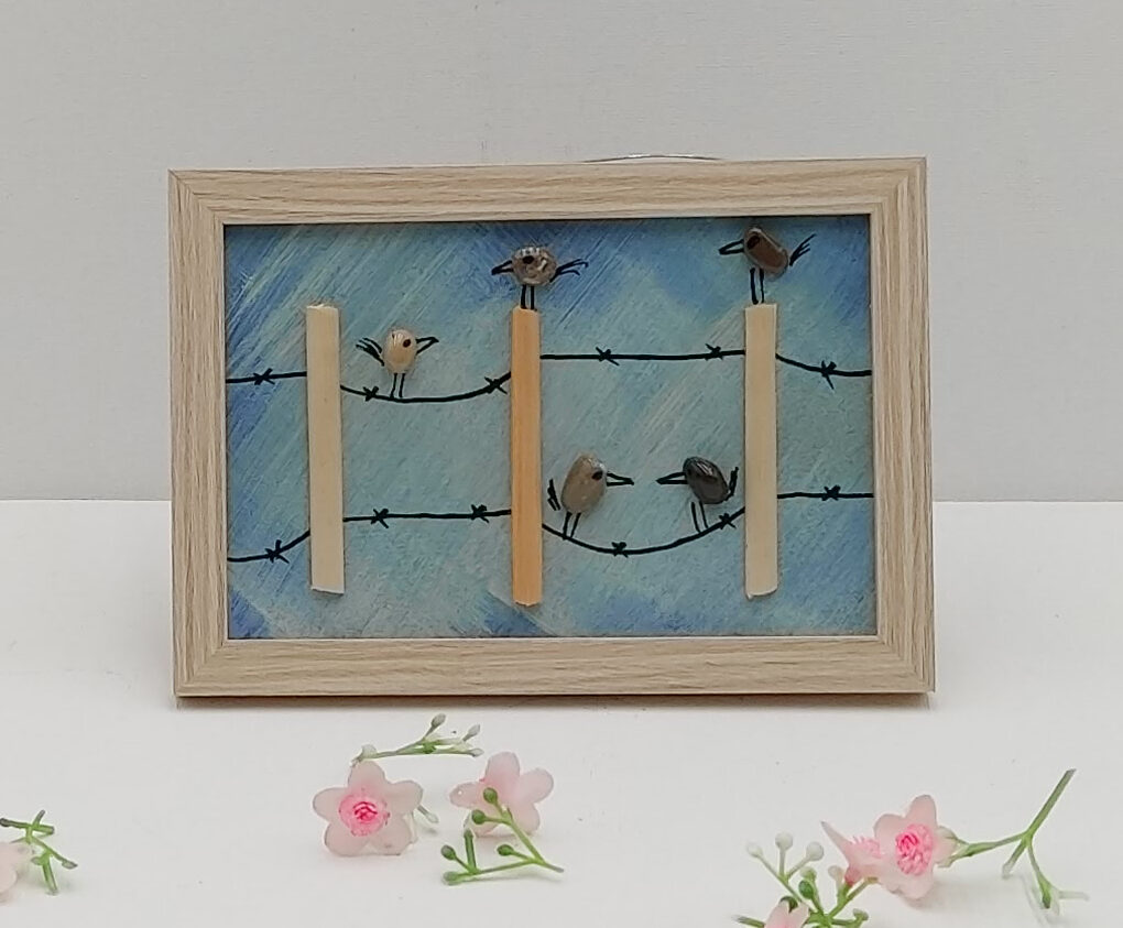 Cinq petits oiseaux perchés sur des fils de fer barbelé